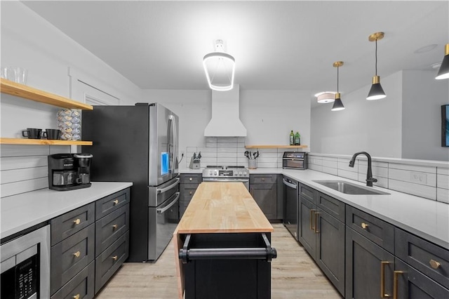 kitchen featuring stainless steel appliances, a sink, custom exhaust hood, and open shelves