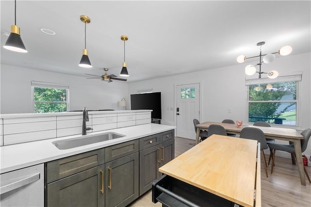 kitchen with ceiling fan, light wood-style flooring, a sink, dishwasher, and decorative light fixtures