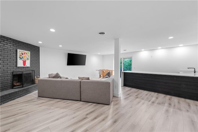 living room featuring a fireplace, visible vents, wood finished floors, and recessed lighting