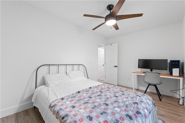 bedroom with ceiling fan, wood finished floors, and baseboards