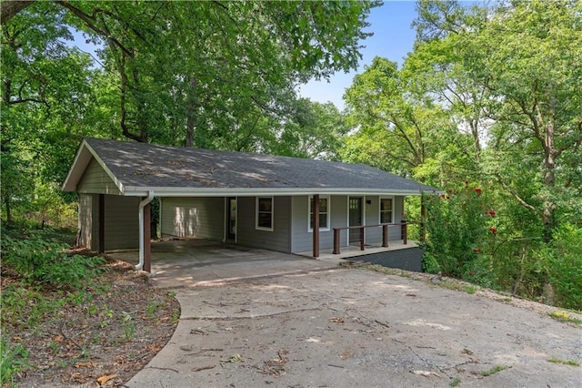 ranch-style home with concrete driveway, a porch, and an attached carport