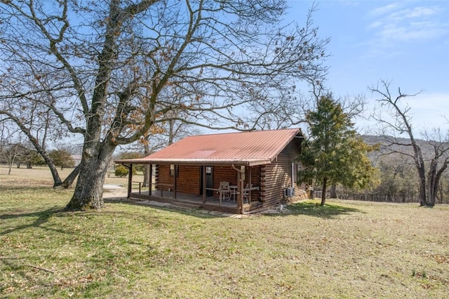 view of front of home featuring covered porch, metal roof, log exterior, and a front yard