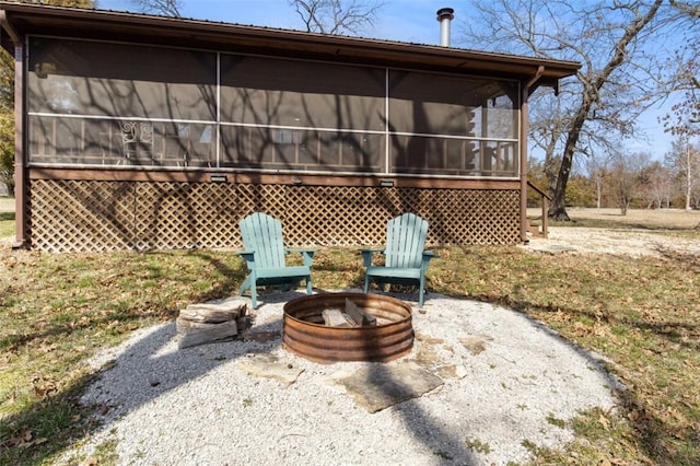 back of property featuring a fire pit, a patio, and a sunroom