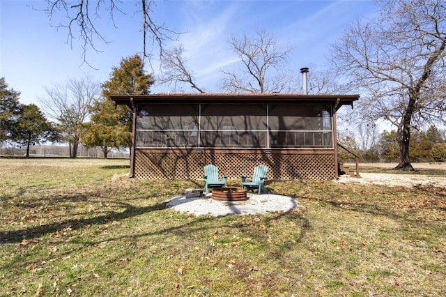 back of house featuring a sunroom, a fire pit, and a lawn