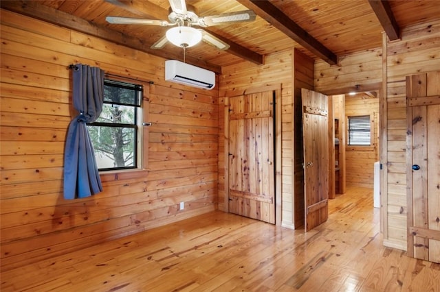 spare room featuring light wood-style floors, wood walls, wooden ceiling, a wall mounted air conditioner, and beamed ceiling