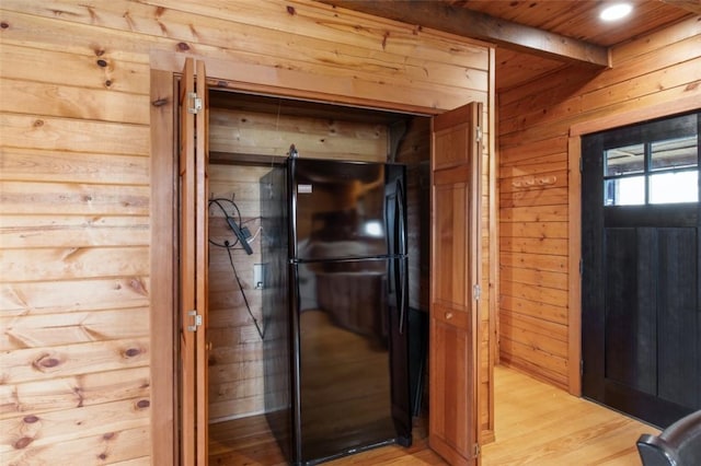 details featuring freestanding refrigerator, beamed ceiling, wooden walls, and wood finished floors