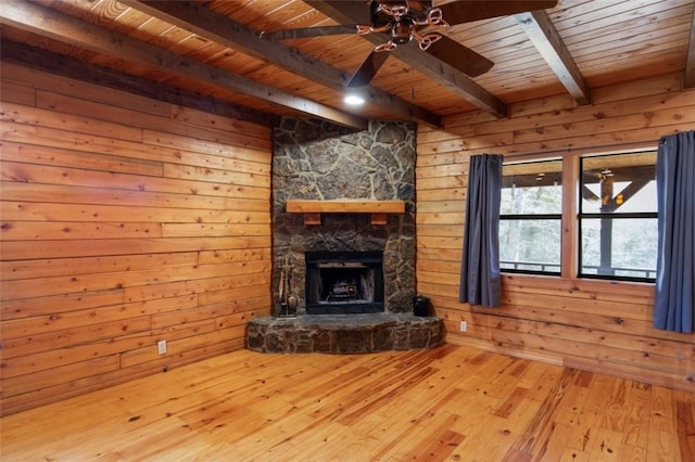 unfurnished living room featuring wooden ceiling, wood walls, a stone fireplace, and hardwood / wood-style flooring