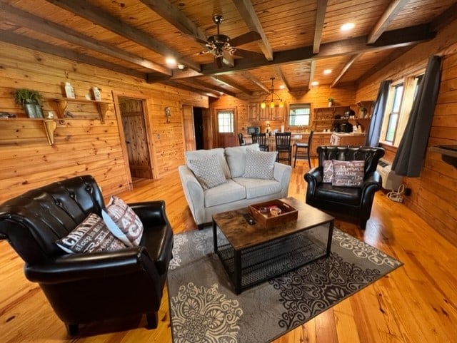 living area featuring a healthy amount of sunlight, wood walls, wood ceiling, and wood finished floors