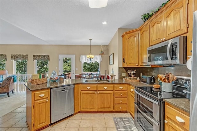 kitchen featuring a peninsula, appliances with stainless steel finishes, light tile patterned flooring, and a sink