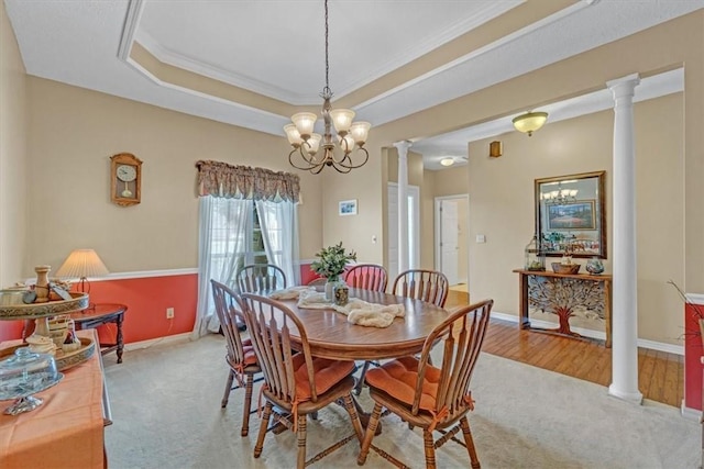 dining space with carpet floors, a tray ceiling, baseboards, and ornate columns