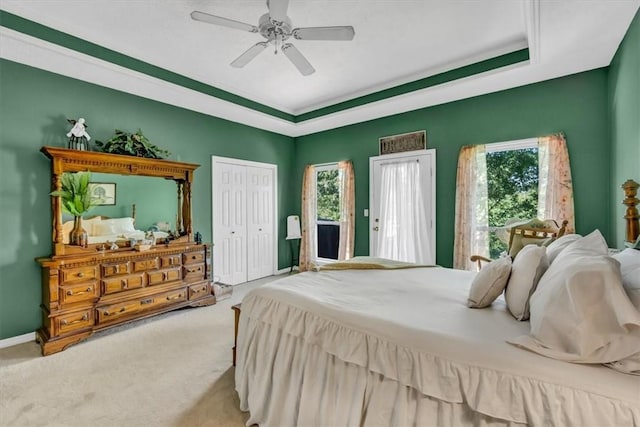 bedroom with baseboards, a ceiling fan, a tray ceiling, carpet floors, and a closet