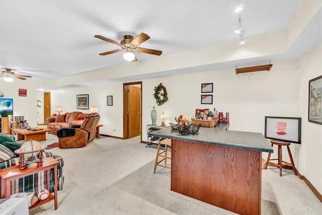 living area with rail lighting, light colored carpet, a ceiling fan, a bar, and baseboards