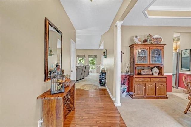 hall featuring decorative columns, baseboards, and light wood-style flooring