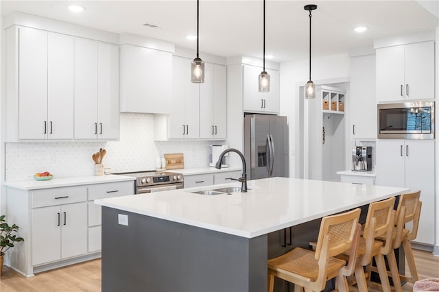 kitchen featuring light wood finished floors, a center island with sink, visible vents, stainless steel appliances, and a sink