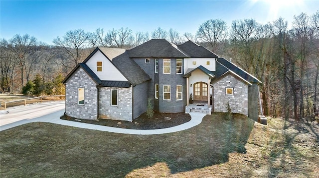 view of front of house with french doors, a standing seam roof, metal roof, stone siding, and a forest view