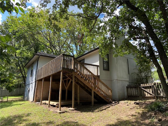 back of house featuring fence, stairway, a deck, and a lawn