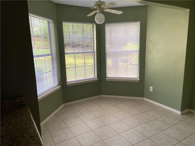 unfurnished dining area with ceiling fan, plenty of natural light, baseboards, and light tile patterned floors