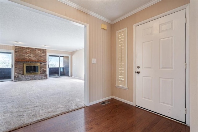 carpeted foyer with a textured ceiling, ornamental molding, a fireplace, and wood finished floors