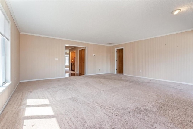 spare room with plenty of natural light, ornamental molding, and light colored carpet