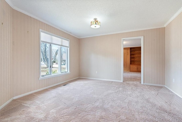 unfurnished room featuring carpet, a textured ceiling, and crown molding