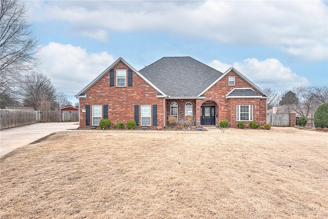 traditional home featuring brick siding, fence, and roof with shingles