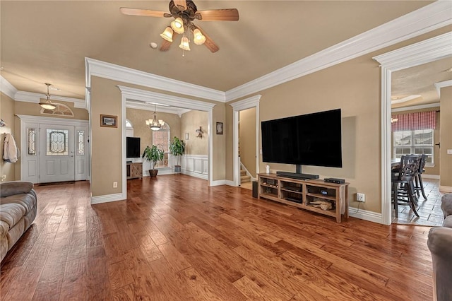 living area with ceiling fan with notable chandelier, hardwood / wood-style floors, ornamental molding, and baseboards