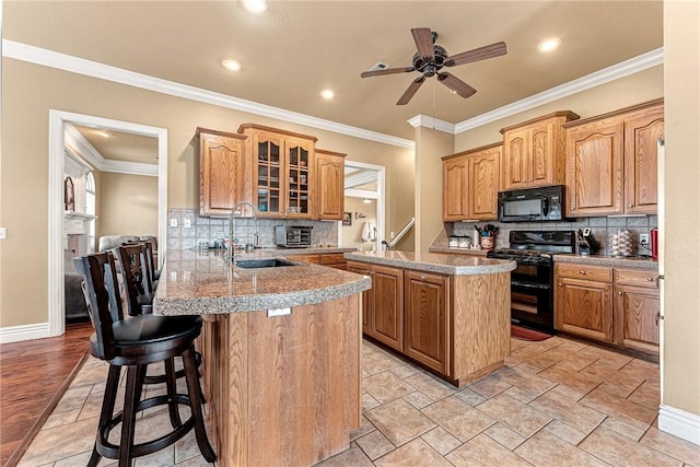 kitchen with glass insert cabinets, a breakfast bar, a peninsula, black appliances, and a sink