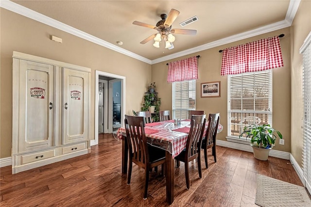 dining space featuring baseboards, crown molding, visible vents, and wood finished floors