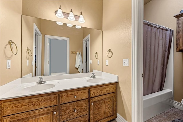 bathroom featuring a sink, shower / bathtub combination with curtain, baseboards, and double vanity