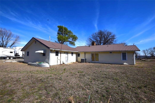 rear view of house with a chimney, metal roof, a lawn, and central air condition unit