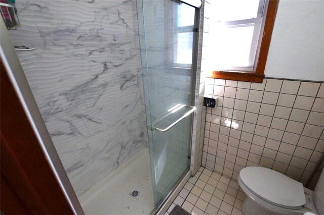 bathroom featuring toilet, a stall shower, tile walls, and tile patterned floors