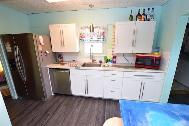 kitchen with appliances with stainless steel finishes, dark wood-style flooring, a sink, and white cabinetry