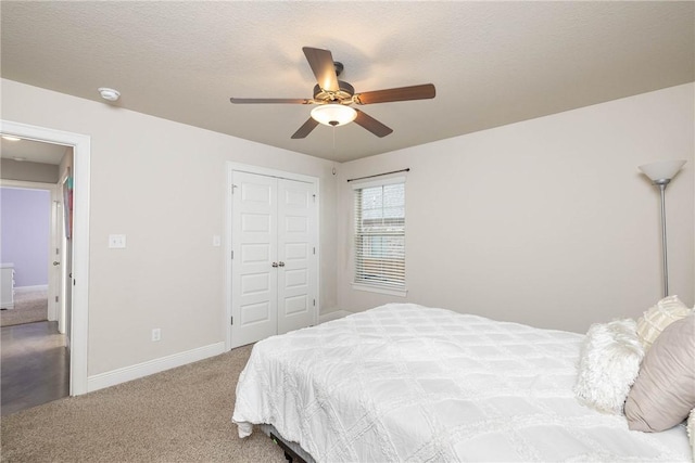 carpeted bedroom with a textured ceiling, ceiling fan, a closet, and baseboards