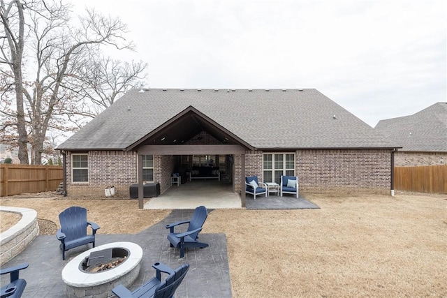 rear view of property with a patio area, an outdoor fire pit, a fenced backyard, and brick siding