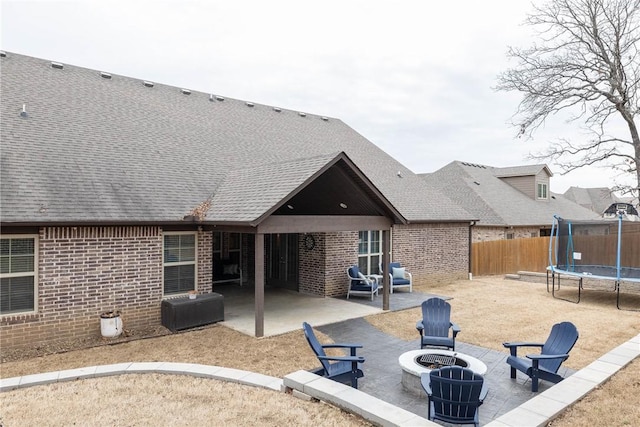 back of house with a trampoline, a patio area, brick siding, and a fire pit