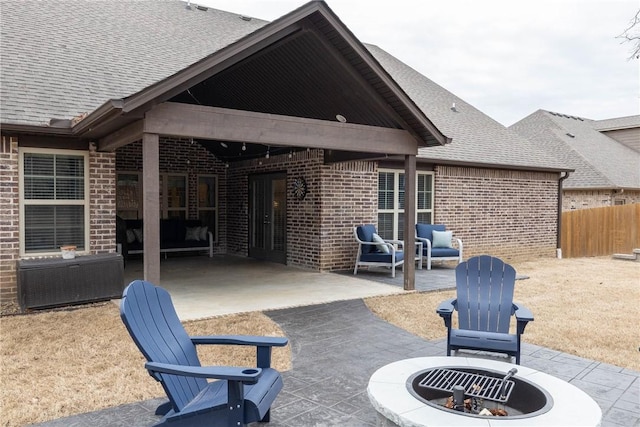 back of property with a fire pit, a patio, brick siding, and a shingled roof