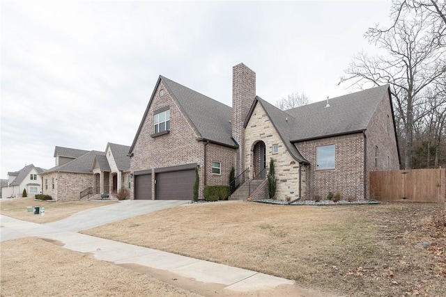 view of front of home with brick siding, a chimney, fence, a garage, and driveway