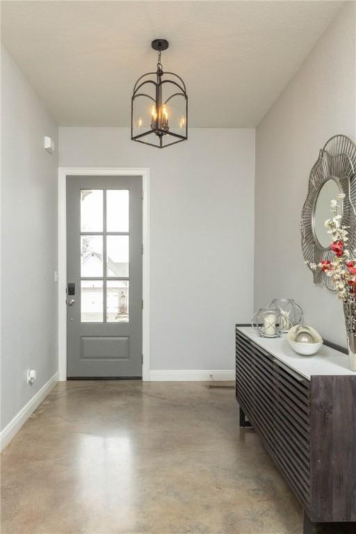 foyer with concrete floors, baseboards, and a chandelier