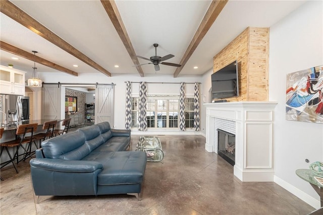 living room featuring beam ceiling, finished concrete flooring, a barn door, a ceiling fan, and baseboards