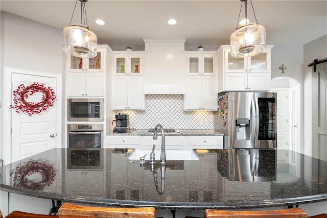 kitchen featuring stainless steel appliances, a barn door, a spacious island, and tasteful backsplash