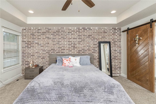 bedroom featuring carpet floors, a barn door, and a tray ceiling