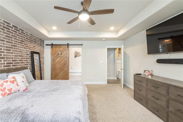 bedroom featuring light carpet, a barn door, baseboards, brick wall, and a tray ceiling