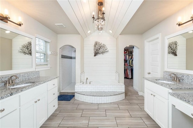 bathroom with a bath, visible vents, two vanities, and a sink