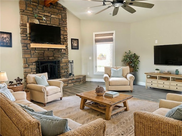 living area with lofted ceiling with beams, a stone fireplace, wood finished floors, and baseboards