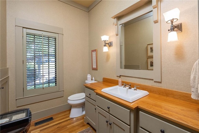 bathroom featuring visible vents, vanity, toilet, and wood finished floors