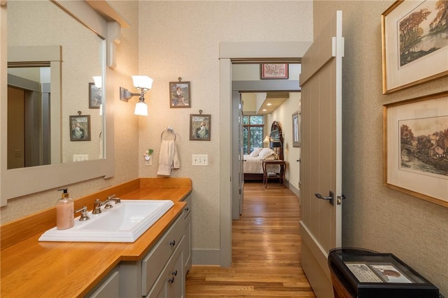 bathroom with baseboards, wood finished floors, and vanity