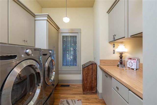 laundry room featuring visible vents, cabinet space, light wood-style flooring, washing machine and dryer, and baseboards