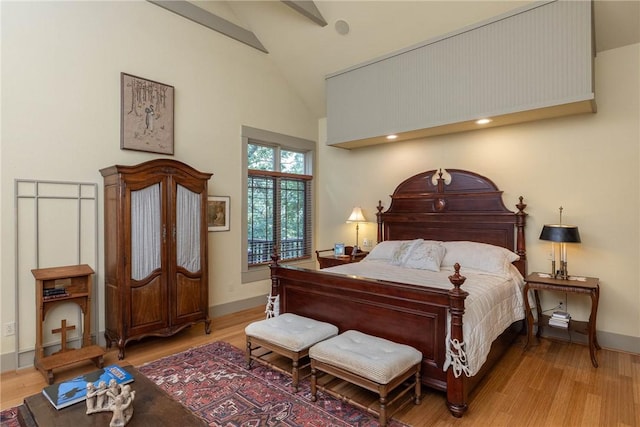 bedroom featuring baseboards, high vaulted ceiling, and wood finished floors