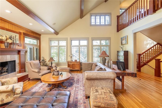 living room with a fireplace, stairway, light wood-style flooring, high vaulted ceiling, and beamed ceiling