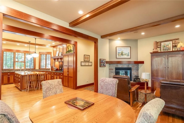 dining room featuring beamed ceiling, a tile fireplace, light wood-style flooring, and recessed lighting